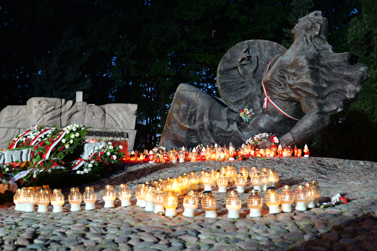 Płonący znicze i wieńce przy Pomniku Polegli Niepokonani na Woli